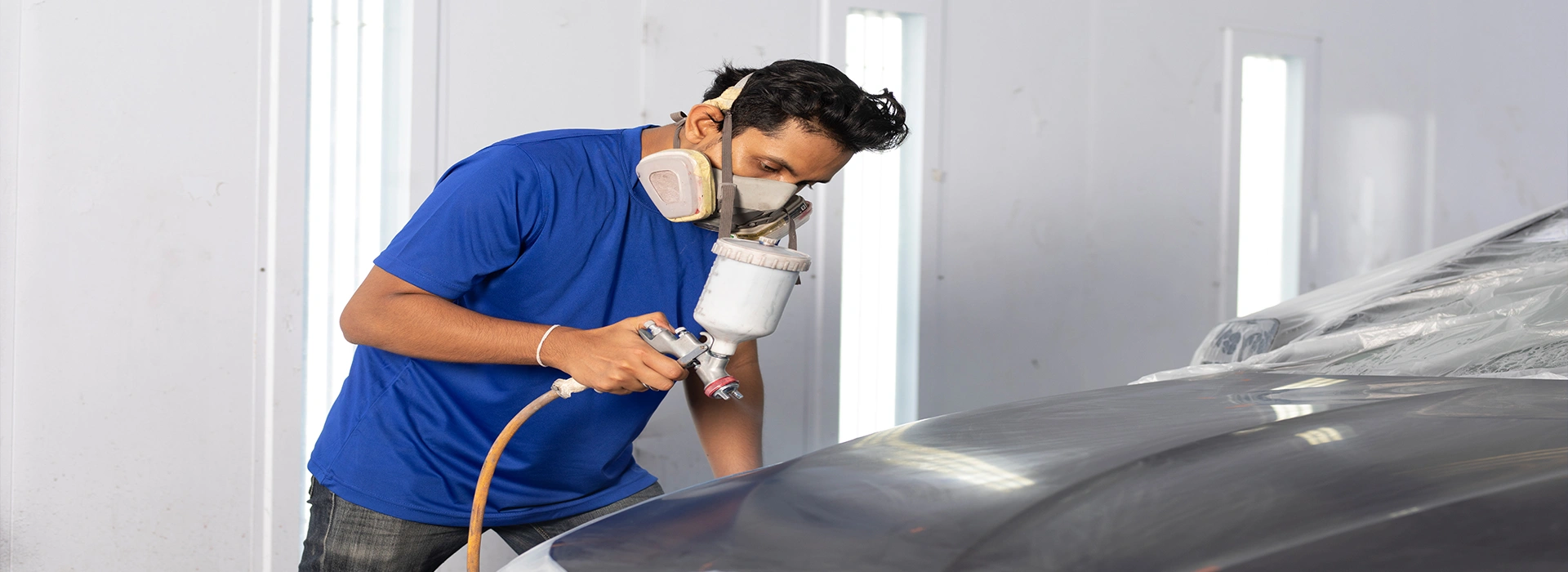 An employee of Mr. Paint Auto auto painting a car