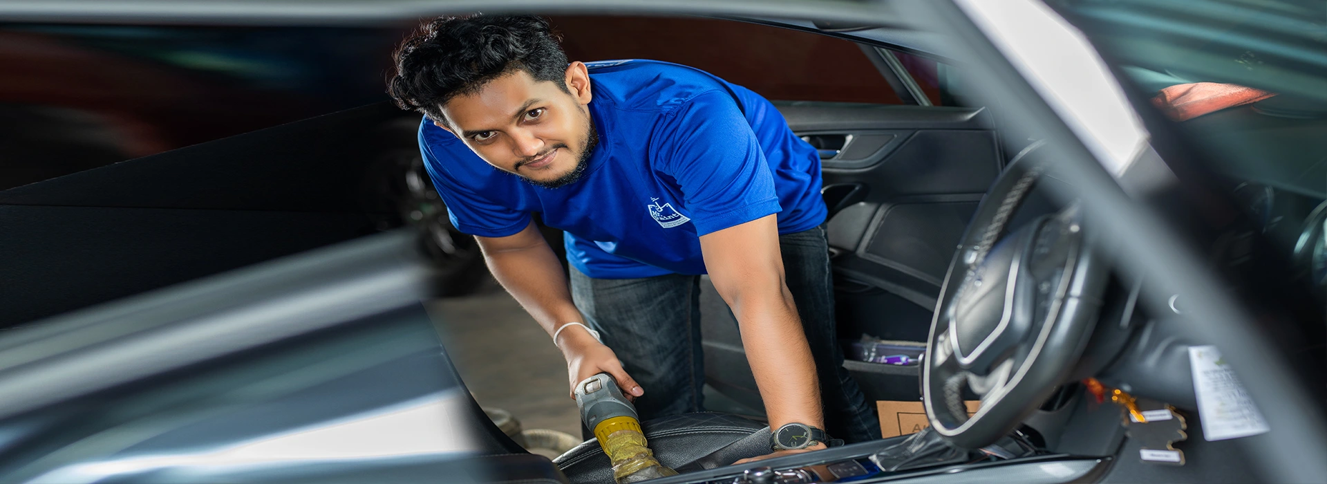 An employee of Mr. Paint Auto working on interior detailing of a car