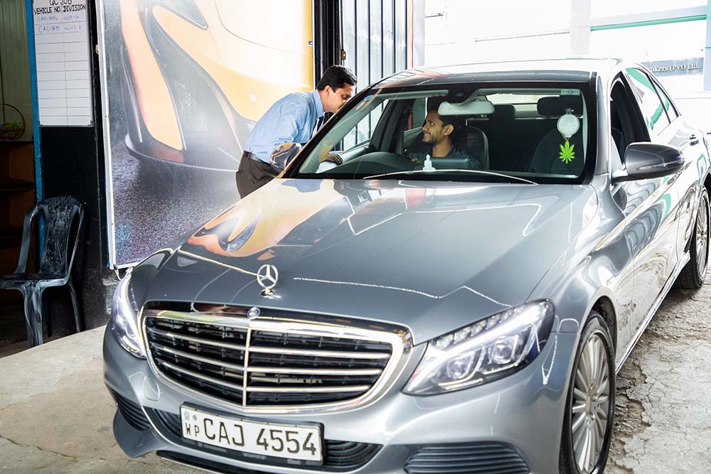 An employee talking to a happy customer in the car at Mr. Paint Auto