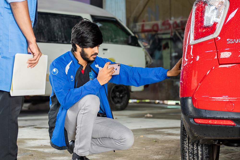 An employee taking a picture of a car at Mr. Paint Auto