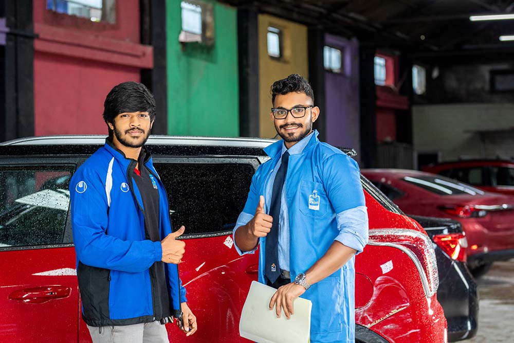 Two young men posing infont of a car at Mr. Paint Auto