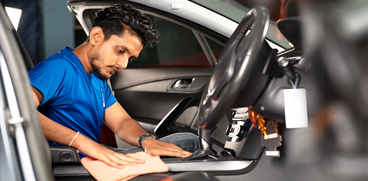 An employee of Mr. Paint Auto working on interior detailing of a car